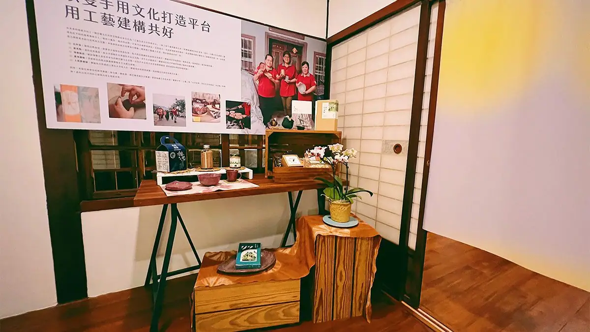 寶來人文協會三位工藝師手持自製陶器合影,身穿檨仔腳品牌制服