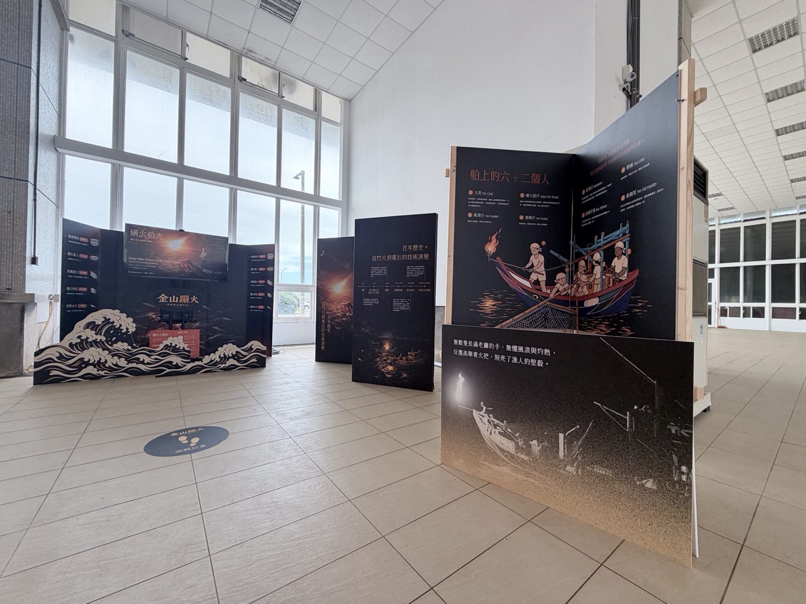 展場整體空間全景，入口紅色浪紋主視覺與多面展板俯瞰動線