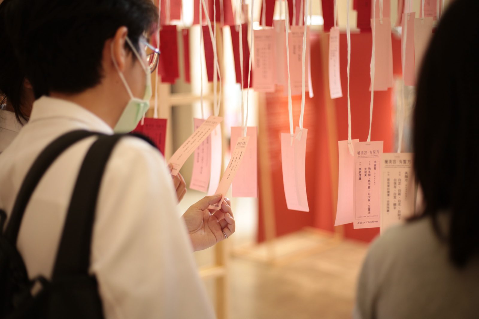 觀眾在展場閱讀懸掛式中醫藥籤紙裝置