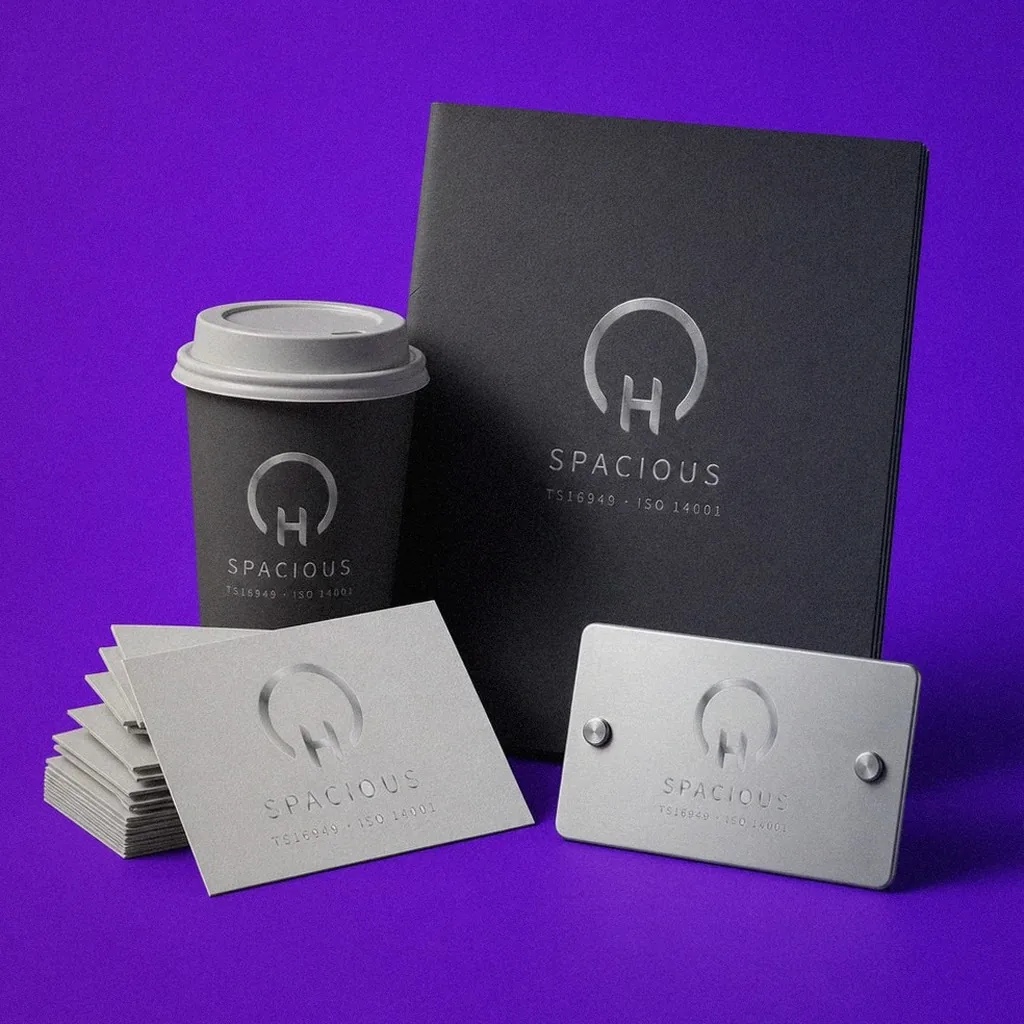 Spacious Enterprise brand application display: paper cups, folders, business cards, and a brass plaque | Howdy Creative